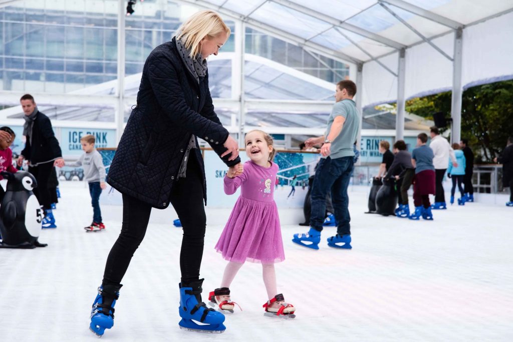 a little girl rides on a city ice rink in winter. High quality photo
